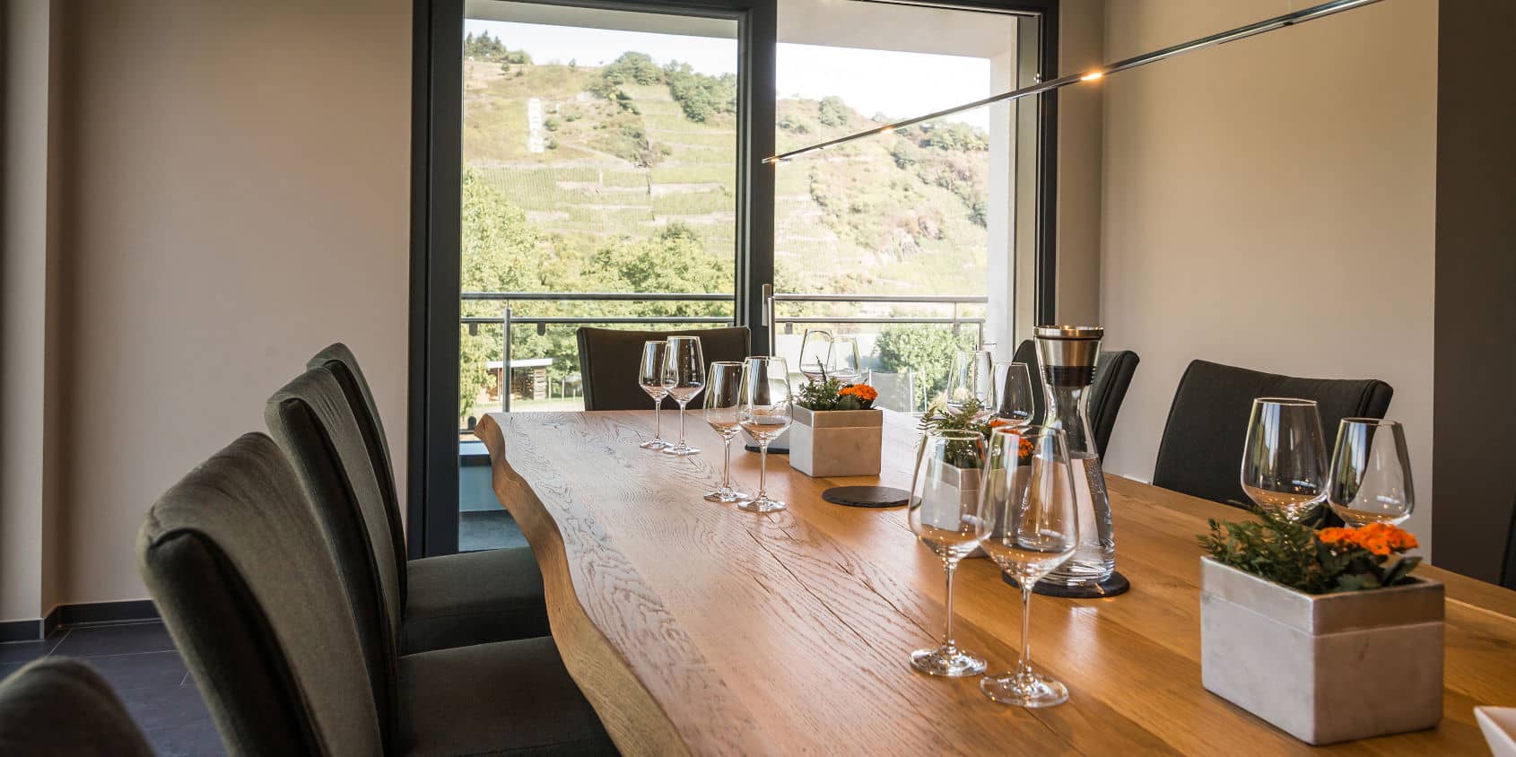 Holztisch mit Weingläsern vor großem Panoramafenster